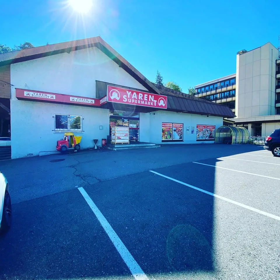 Der Yaren Supermarkt von der Straße aus, mit dem roten Firmenschild über dem Eingang und dem Parkplatz davor