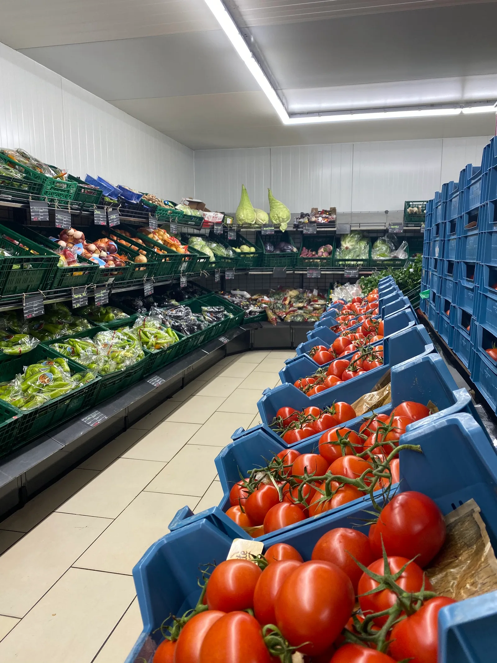 Gemüseabteilung mit Paprika, Zwiebeln und gestapelten Tomatenkisten